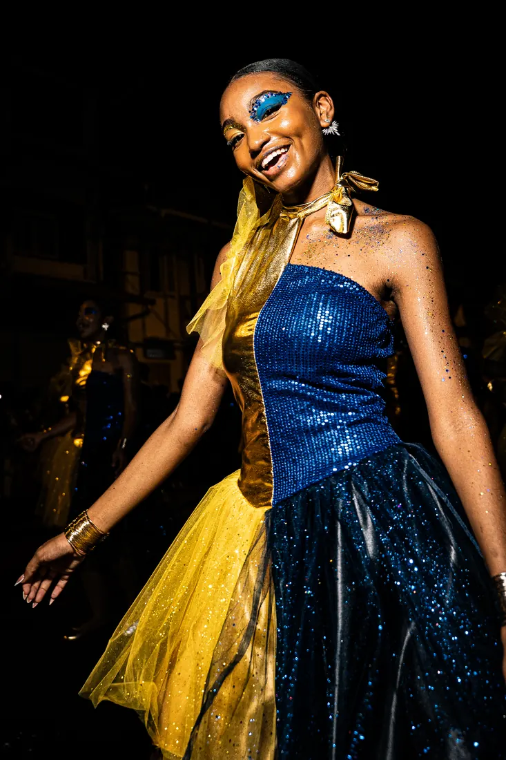 RGR SHOOT, danseuse en robe bleue et dorée, maquillage à paillettes, pendant un défilé de nuit